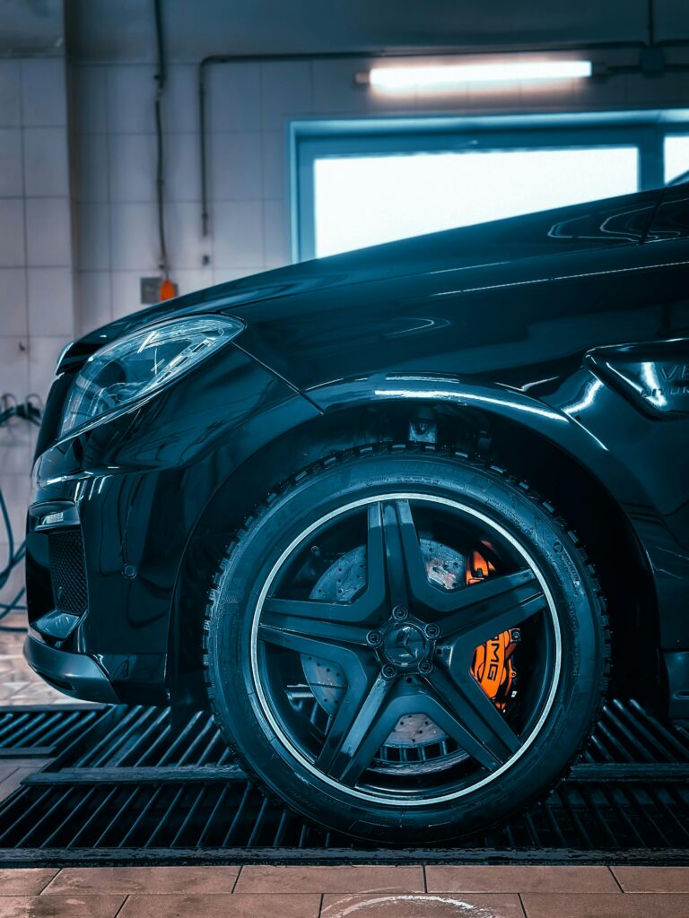 pexels-photo-31014470-31014470 Detailed close-up of a luxury car wheel and brake system in a garage environment.