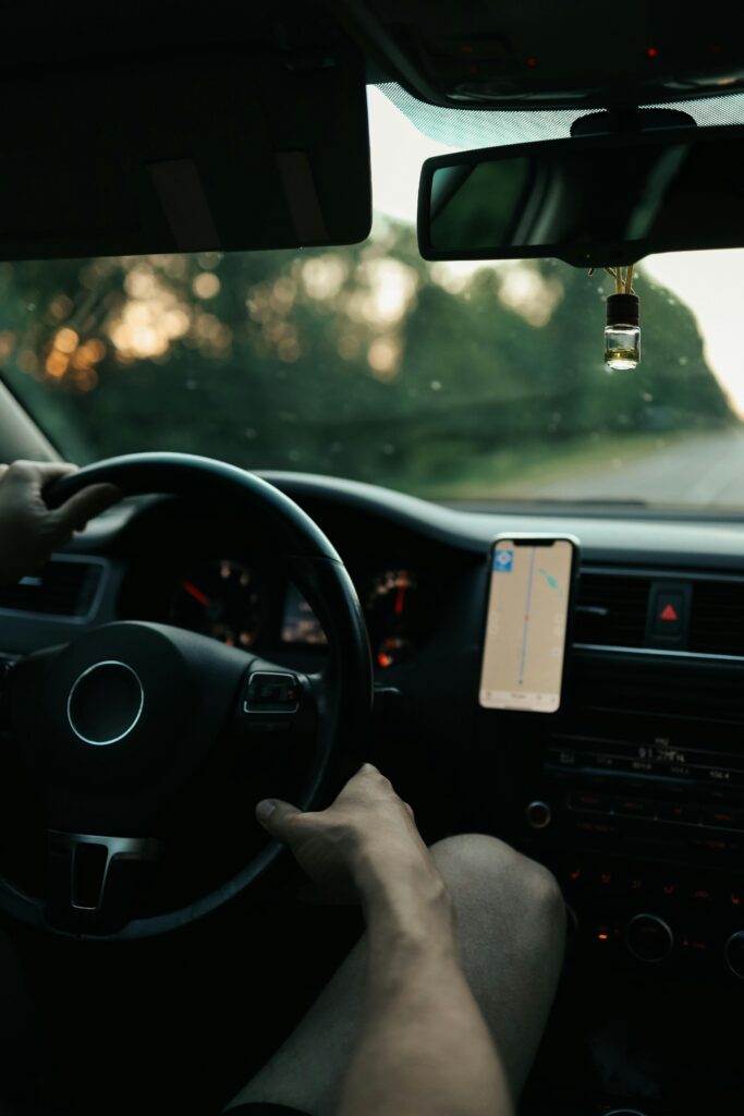 View from inside a car showing hands on the wheel, driving with a GPS-guided journey.