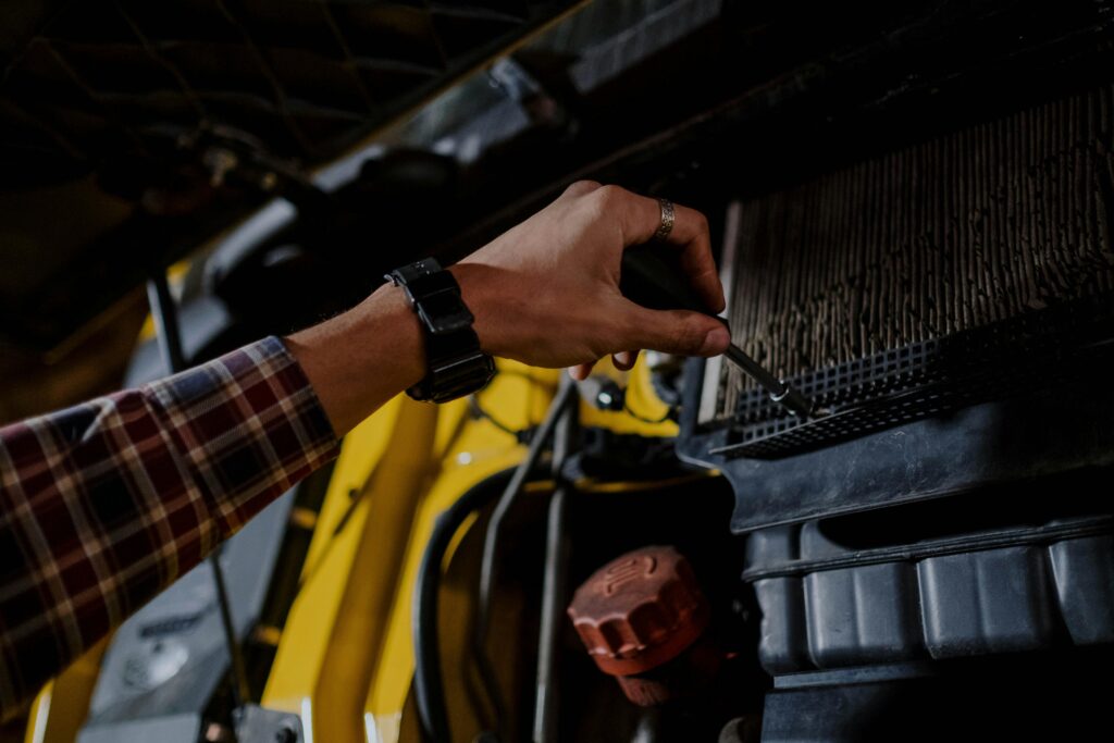 pexels-photo-7541358-7541358 Close-up of a mechanic's hand using a screwdriver to inspect a vehicle's engine.